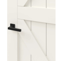 Detailopname van een witte binnendeur in landelijke stijl met een moderne zwarte deurklink.