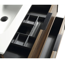 Open lade van een wastafelmeubel in houtlook met een grijze lade-indeling voor badkameraccessoires en een witte wastafel.