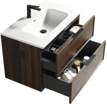 Modern badkamermeubel met houtlook kast, witte wastafel en zwarte kraan. Twee open lades tonen opbergruimte en accessoires.