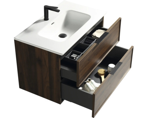 Modern badkamermeubel met houtlook kast, witte wastafel en zwarte kraan. Twee open lades tonen opbergruimte en accessoires.
