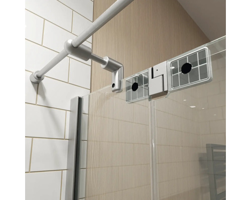 Detail van een douchecabine met een metalen stabilisatiestang, een glazen wand en witte wandtegels.