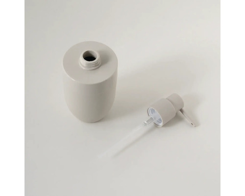 Beige zeepdispenser van keramiek, gedemonteerd in flacon en pompkop met stijgbuis.