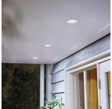 Ronde inbouwspots in een houten terrasoverkapping voor subtiele buitenverlichting.