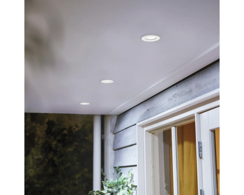 Ronde inbouwspots in een houten terrasoverkapping voor subtiele buitenverlichting.