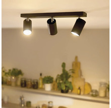 Moderne plafondlamp met drie cilindervormige spots gemonteerd op een rechthoekige rail in een woonruimte