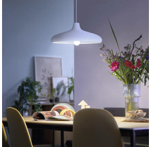 Moderne hanglamp boven een eettafel in een lichte, sfeervolle eetkamer met een boeket bloemen en decoratie.
