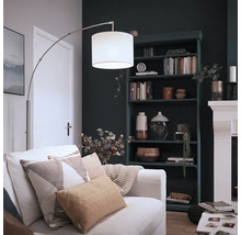 Moderne booglamp met stoffen kap en metalen frame in een gezellige woonkamer met boekenkast en open haard.