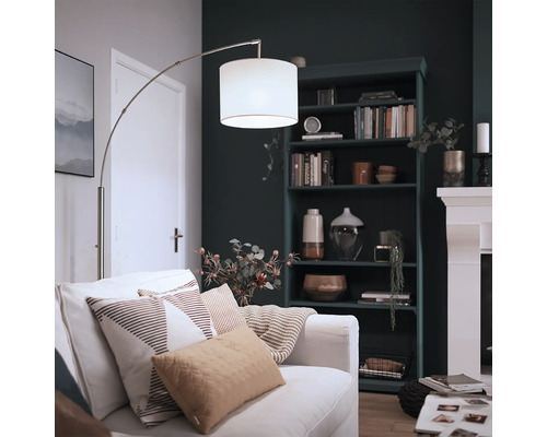 Moderne booglamp met stoffen kap en metalen frame in een gezellige woonkamer met boekenkast en open haard.