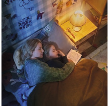 Moeder en kind lezen samen een boek in de kinderkamer bij het gezellige licht van een nachtlampje.