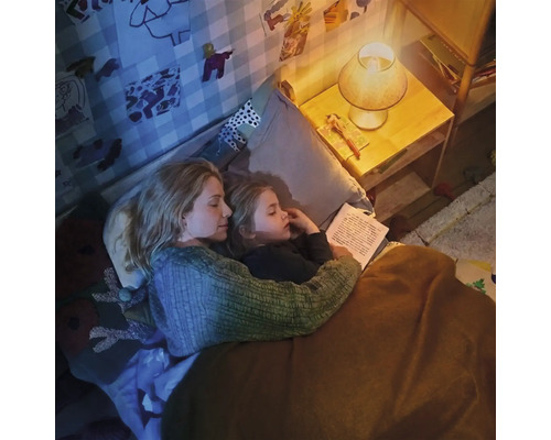 Moeder en kind lezen samen een boek in de kinderkamer bij het gezellige licht van een nachtlampje.