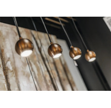 Vier ronde hanglampen met een modern ontwerp en bolvormige lampenkappen in metaaloptiek hangen aan het plafond.