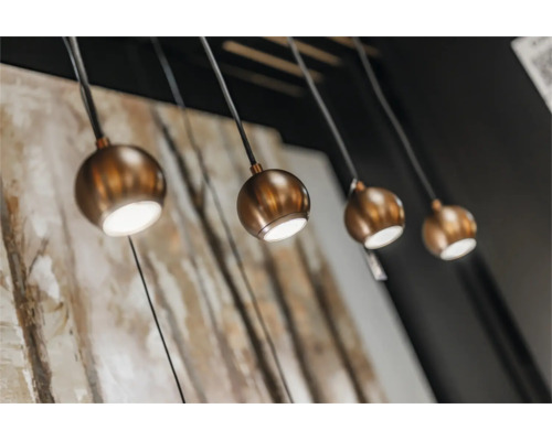 Vier ronde hanglampen met een modern ontwerp en bolvormige lampenkappen in metaaloptiek hangen aan het plafond.