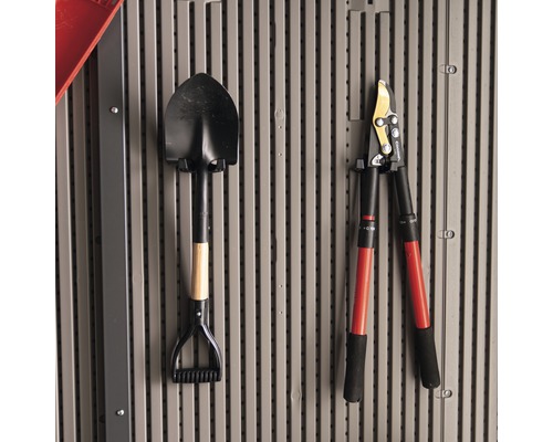 Een spade en een takkenschaar hangen aan de muur.