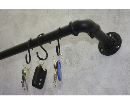 Sleutelbord van ijzeren buis met S-haken en sleutels aan grijze muur