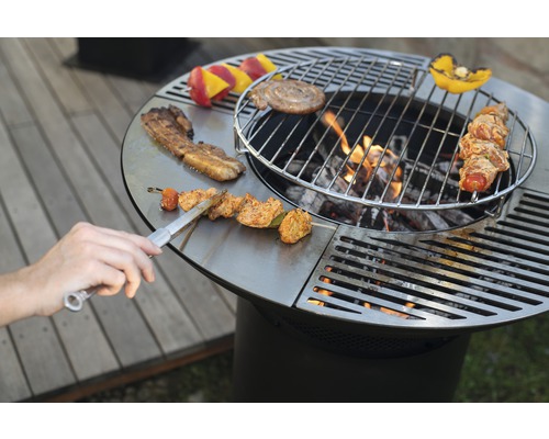 Ronde barbecue met eten en barbecuetang op het grilloppervlak