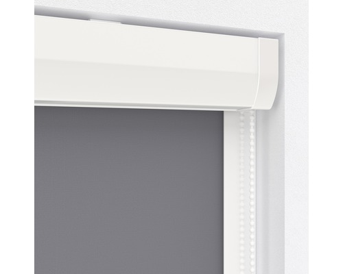 Detailopname van een grijs rolgordijn met witte cassette en bedieningsketting.
