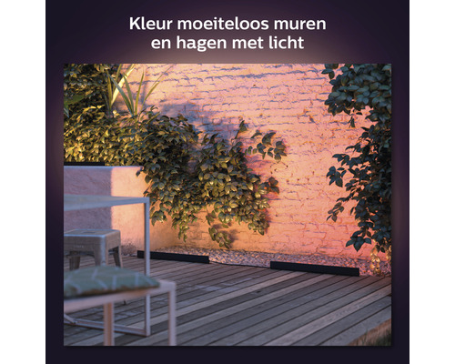 Verlichte tuinmuur met planten op houten terras