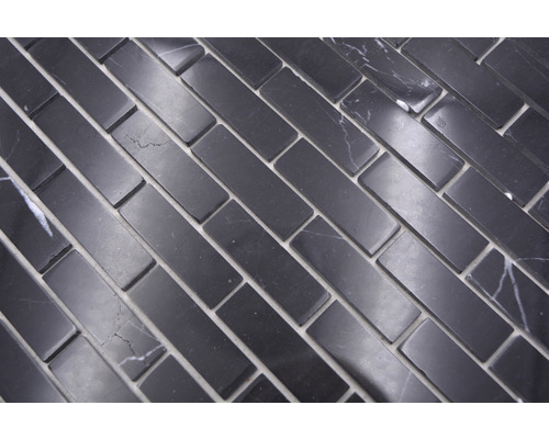 Rechthoekige mozaïektegels van natuursteen, gelegd in visgraatmotief.