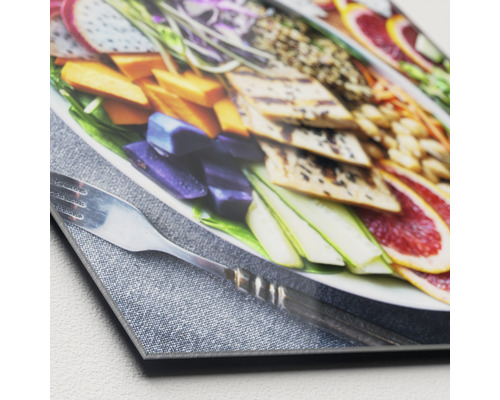 Close-up van een acrylglas foto met een voedselscène, inclusief fruit en groenten, met een vork