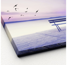 Canvas schilderij met een bank aan het meer en vliegende vogels