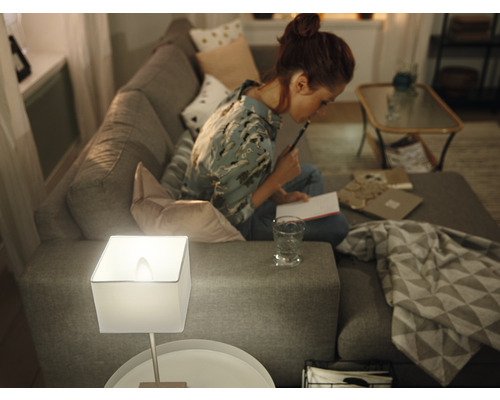 Woonkamer met lamp op bijzettafel en vrouw op de bank