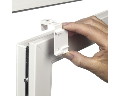 Persoon bevestigt een jaloeziehouder aan een raamkozijn.