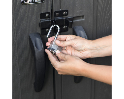 Iemand sluit een hangslot aan een schuur.