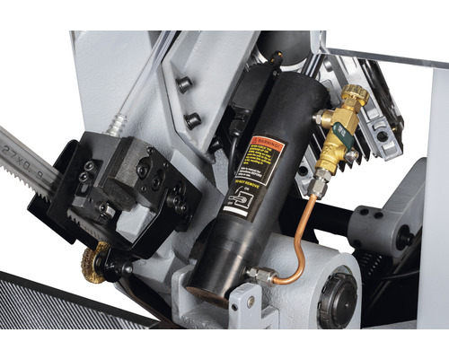 Detailopname van een metaalzaag met hydraulische cilinder en koelvloeistoftoevoer