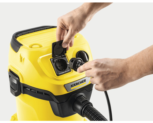 Een gele Kärcher stofzuiger wordt aangesloten op een stopcontact.