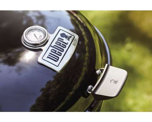 Detailopname van een kogelbarbecue met Weber logo, temperatuurmeter en dekselgreep