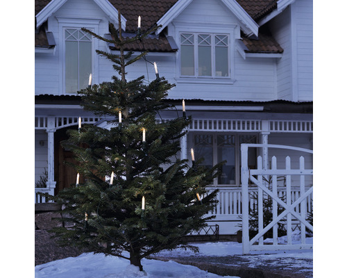 Kerstboom met elektrische kaarsverlichting voor een huis