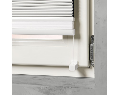 Gedetailleerde weergave van een wit plisségordijn op een raam