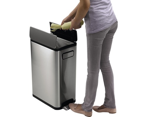 Vrouw gooit mais in een roestvrijstalen pedaalemmer