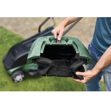 Persoon houdt de grasopvangbak van een grasmaaier vast