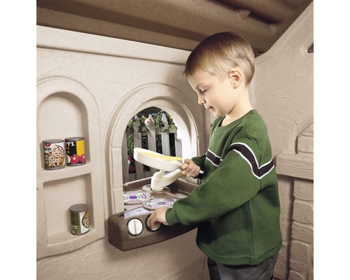 Jongen speelt met speelgoedkeuken in speelhuis