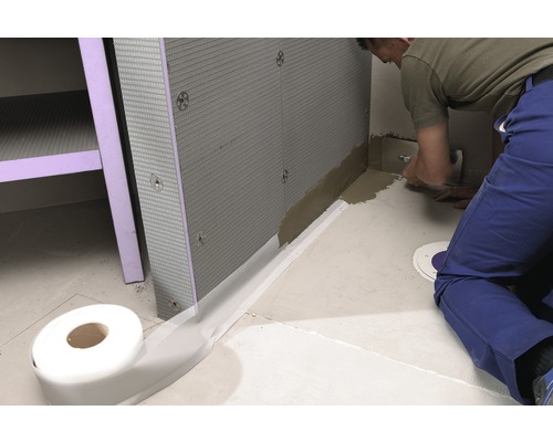 Een vakman voegt een douchewand af met afdichtband.