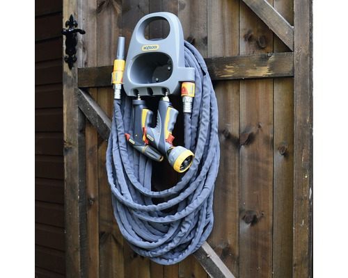 Tuinslang met houder en spuitpistool gemonteerd aan een houten wand