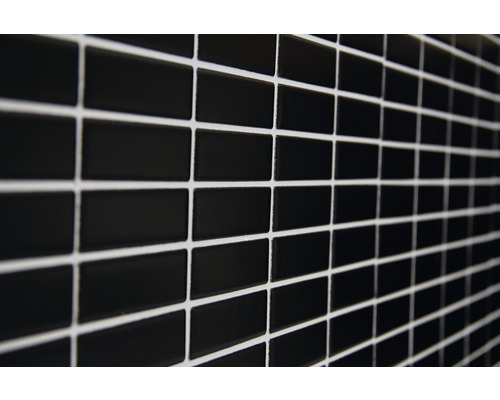 Muur van zwarte, rechthoekige tegels met lichte voegmortel