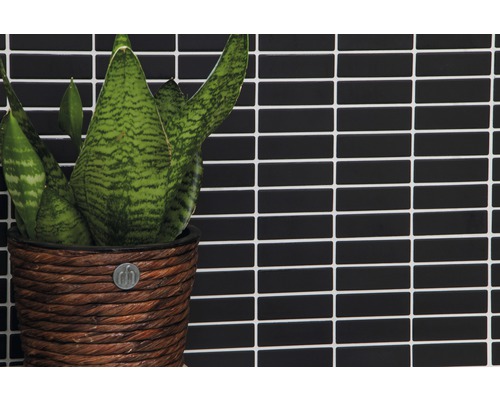 Plant in gevlochten pot voor een wand van rechthoekige tegels