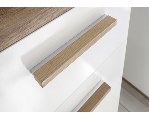 Detailopname van een wit meubelstuk met houten handgrepen