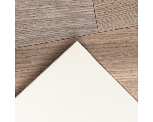 Close-up van een witte wandtegel op een houten vloer