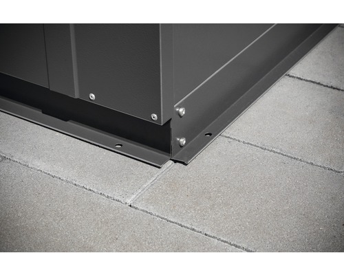 Detailopname van een hoek van een tuinhuis met bevestiging op straatstenen