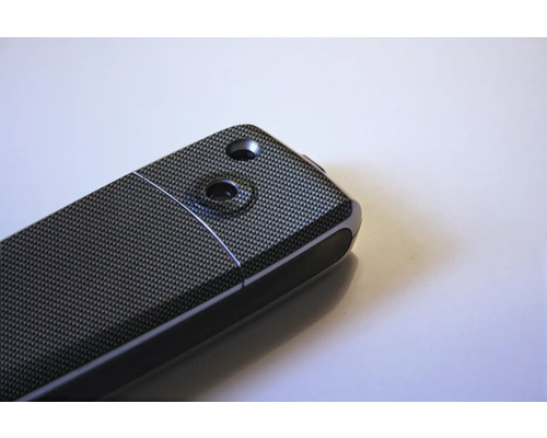 Gedetailleerde weergave van een elektronisch apparaat met koolstofvezelpatroon en twee uitsparingen.