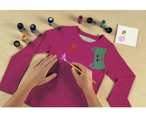 Het beschilderen van een roze shirt met lange mouwen met textielverf, kwast en verfbakje