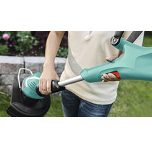 Persoon houdt een grastrimmer in een tuin vast.