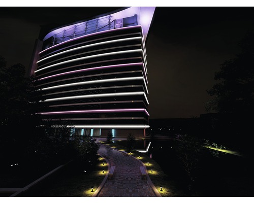 Buitenaanzicht van een modern kantoorgebouw ''s nachts met decoratieve verlichting en pad