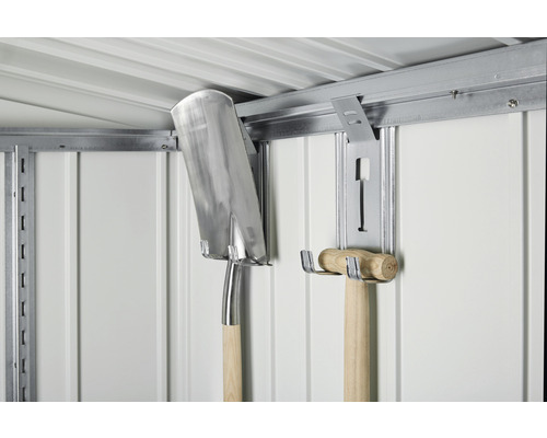 Tuinaccessoires zoals een spade en een hamer hangen aan een metalen wandhouder in een tuinhuis.