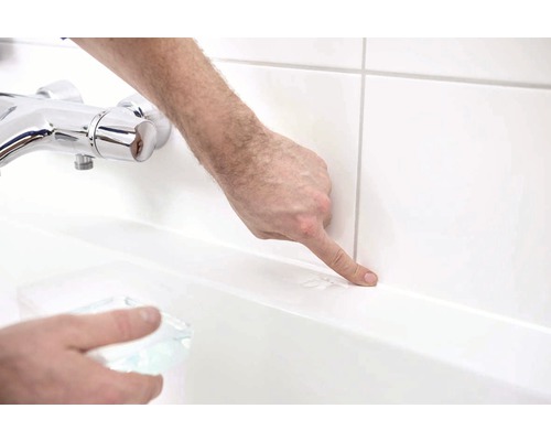 Persoon wijst met vinger naar een voeg in de badkamer