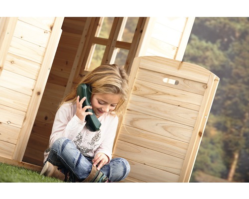 Meisje zit met een speelgoedtelefoon in een houten speelhuis