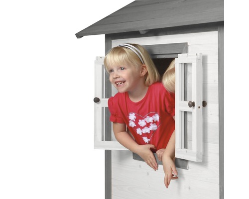 Meisje kijkt uit het raam van een houten speelhuis